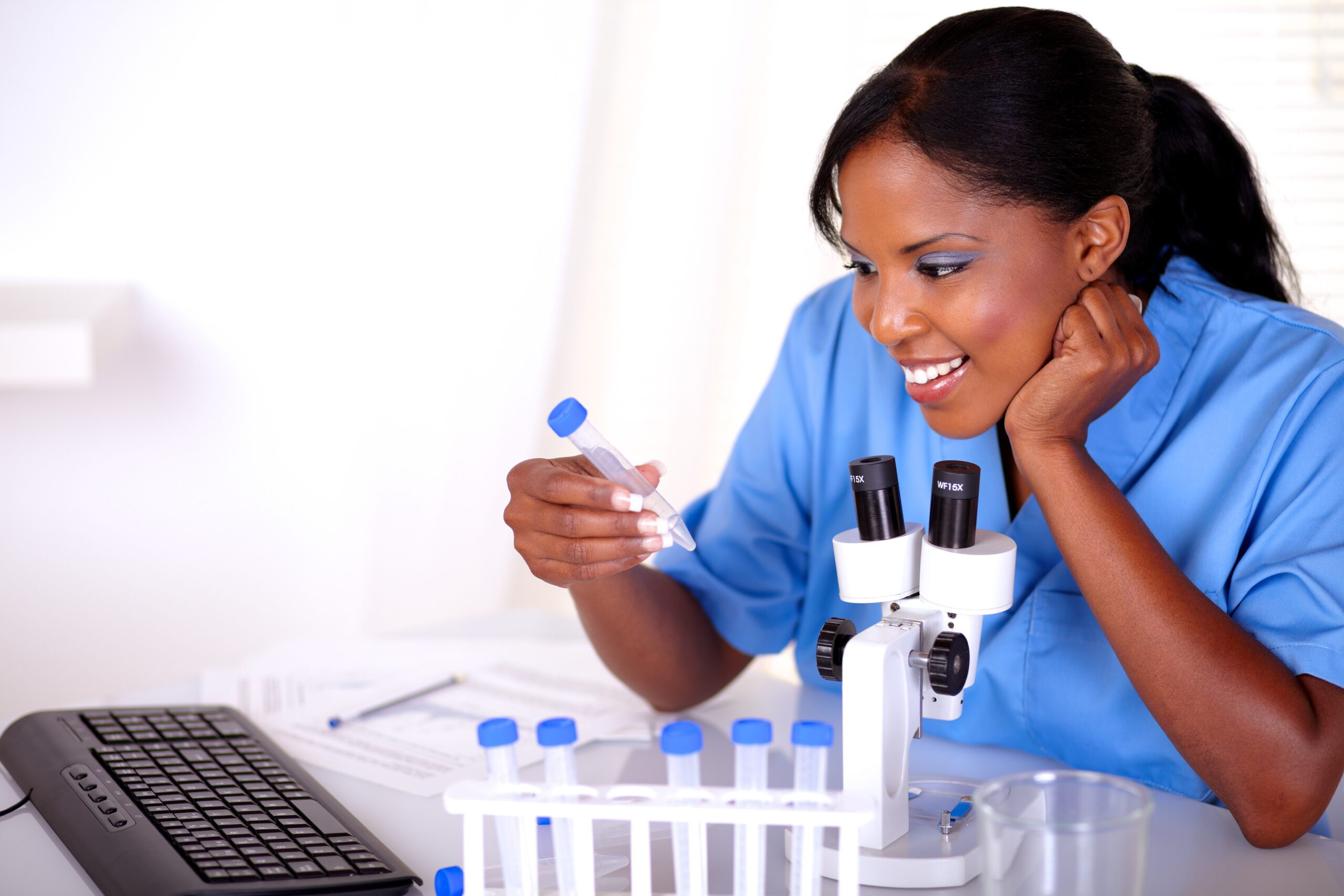 Scientific young female working at laboratory with microscope and tube test