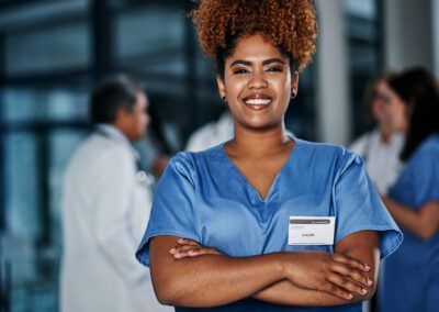 Portrait of a confident young doctor working in a hospital with her colleagues in the background.